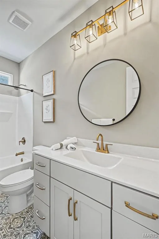 Bathroom featuring a white vanity with quartz-finish countertop, gold-tone faucet, and decorative floor tiling — 312 Summer Glen Lane, St Charles, MO 63301
