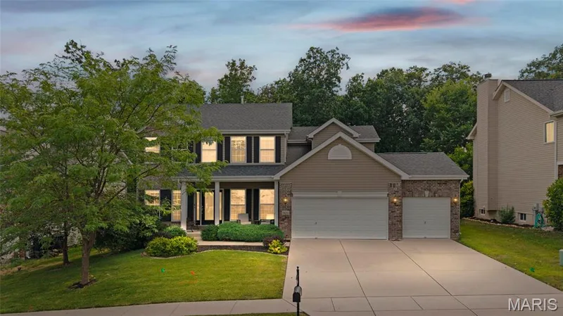 Virtual Night Photo -Two-story residence featuring a covered front porch with white columns, a three-car garage, and stone veneer accents — 921 Molloy Drive, O'Fallon, MO 63366