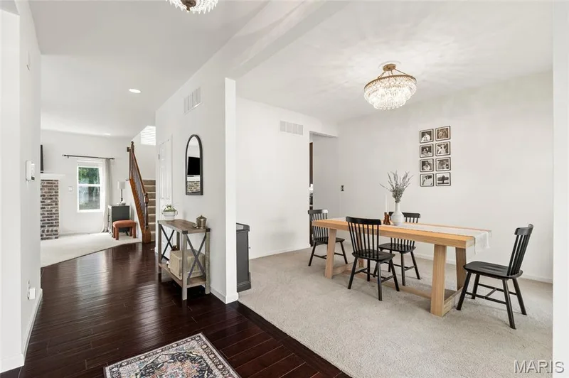Bright dining area featuring a tiered crystal chandelier, light carpet, and white walls — 921 Molloy Drive, O'Fallon, MO 63366