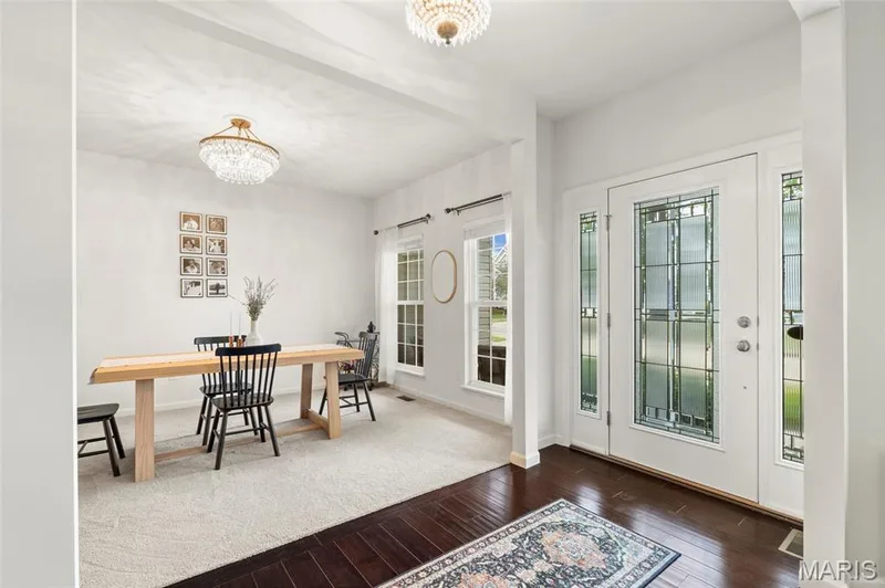 Inviting entry foyer featuring dark wood-finish flooring, a white paneled front door with decorative glass inserts, and matching sidelights — 921 Molloy Drive, O'Fallon, MO 63366