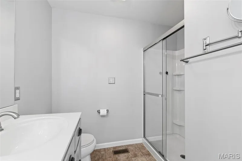 Bathroom featuring a glass-enclosed shower, single vanity with integrated sink, brushed nickel faucet, and neutral wall paint — 921 Molloy Drive, O'Fallon, MO 63366
