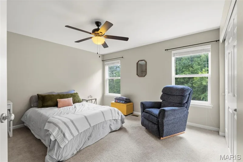 Second Bedroom featuring neutral wall tones, carpeted flooring, a ceiling fan with integrated lighting, and two windows with blinds. — 921 Molloy Drive, O'Fallon, MO 63366