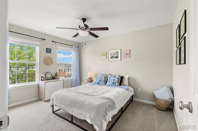 3rd Spacious room with WALK-IN closet featuring neutral-toned walls, plush carpet flooring, two double-hung windows, and a ceiling fan with integrated lighting — 921 Molloy Drive, O'Fallon, MO 63366