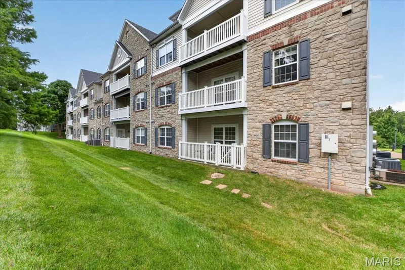 Multi-level residential building featuring stone and siding exterior, multiple balconies with white railings, and arched window details — 5 Monarch Trace Court #108, Chesterfield, MO 63017