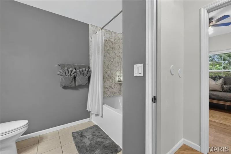 White bathtub and shower combination featuring a stone-look tiled surround — 5 Monarch Trace Court #108, Chesterfield, MO 63017