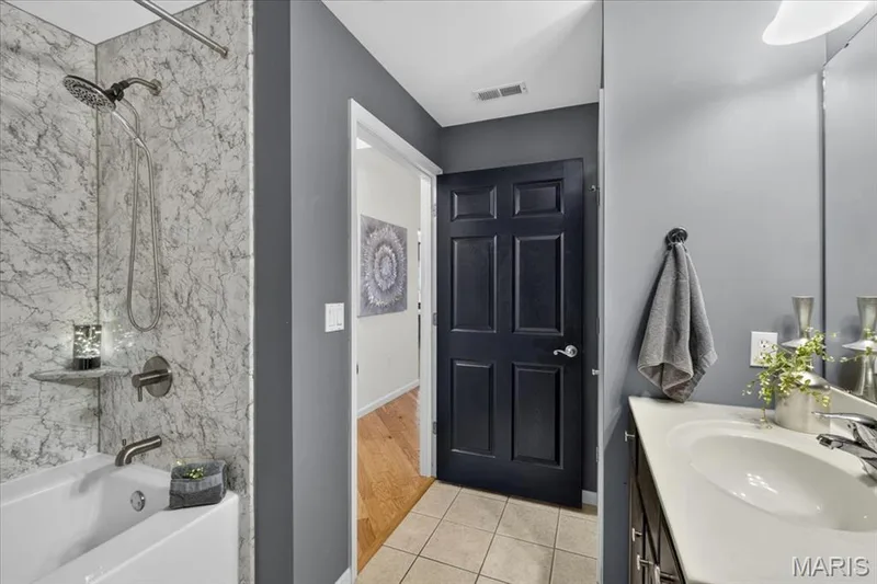 Bathroom featuring a white drop-in sink, dark wood-finish vanity with hardware, and a large wall-mounted mirror — 5 Monarch Trace Court #108, Chesterfield, MO 63017