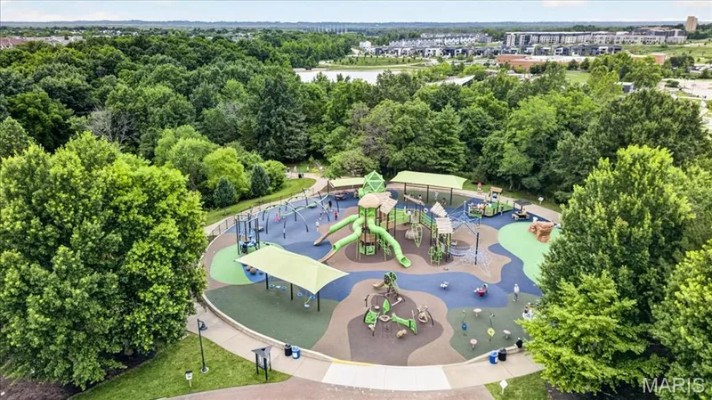 Spacious recreational playground featuring multiple play structures, soft-surface flooring, shade canopies, and surrounding mature trees — 5 Monarch Trace Court #108, Chesterfield, MO 63017