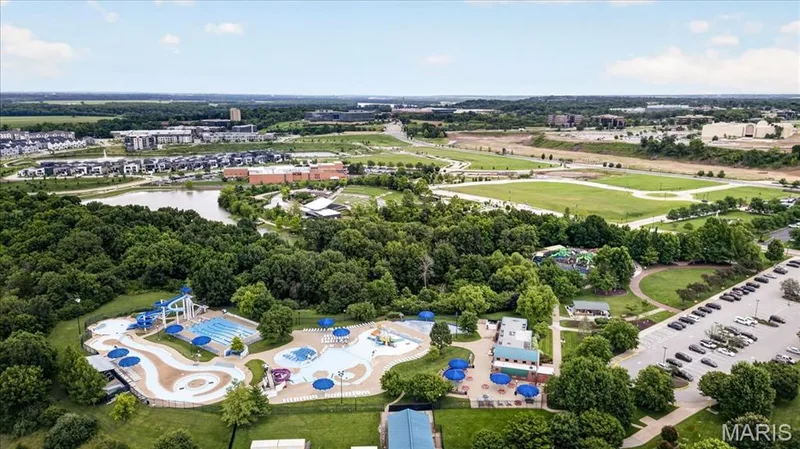 Aerial perspective showcasing the aquatic center with multiple pools, water slides, and shade structures — 5 Monarch Trace Court #108, Chesterfield, MO 63017