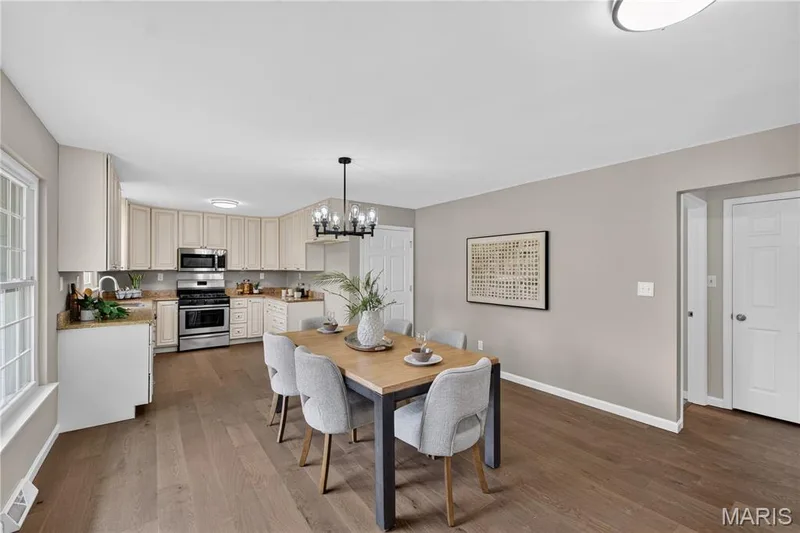 Open-concept living space featuring wood-finish flooring, a kitchen with light-toned cabinetry, stainless steel appliances, and granite countertops — 33 Timber Ridge Drive, Marthasville, MO 63357