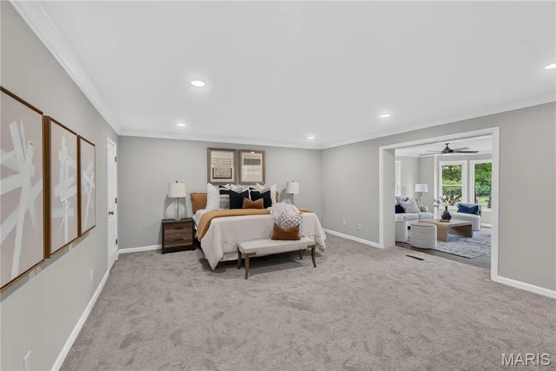 Spacious room featuring light gray carpeting, recessed lighting, white crown molding, and a wide cased opening to an additional living area — 33 Timber Ridge Drive, Marthasville, MO 63357