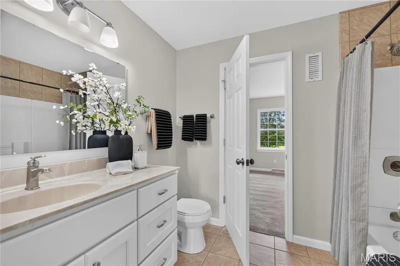 Bathroom featuring a single vanity with stone-finish countertop, brushed nickel faucet, and white cabinetry — 33 Timber Ridge Drive, Marthasville, MO 63357