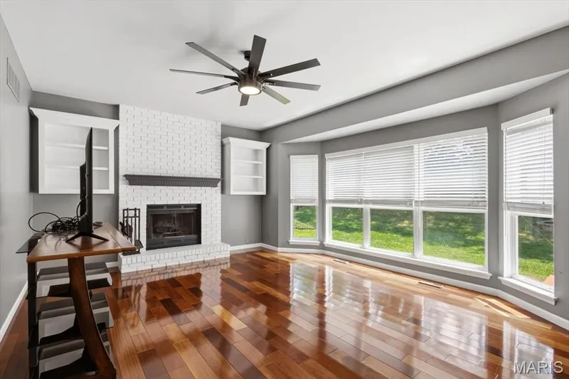 The family room features a wood-burning fireplace, flanked by shelves, bay window and gleaming hardwood floor. — 175 Beacon Point Lane, Wildwood, MO 63040