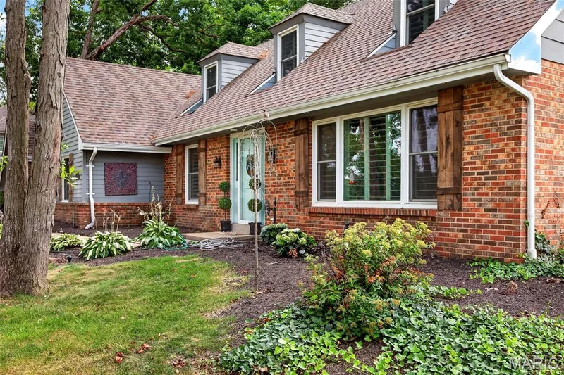Brick exterior with gray siding accents, dormer windows, natural wood shutters, and a light blue entry door — 4 Chantilly Court, Lake St. Louis, MO 63367