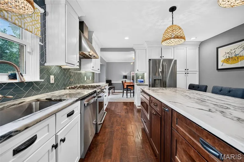 Gourmet kitchen with two-tone cabinetry, stainless steel appliances, and a substantial island featuring a stone countertop — 4 Chantilly Court, Lake St. Louis, MO 63367