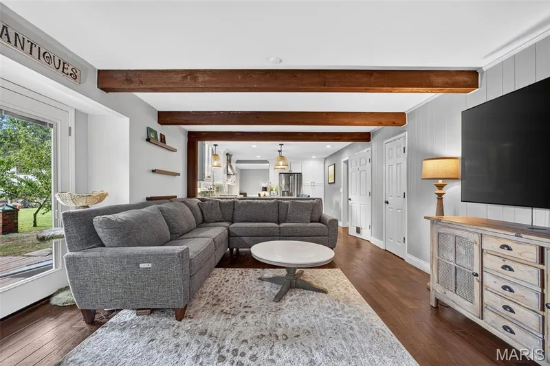 Living space featuring wood-finish flooring, exposed ceiling beams, and light wall finishes — 4 Chantilly Court, Lake St. Louis, MO 63367