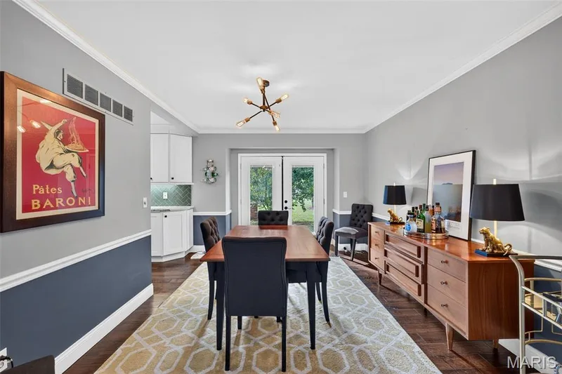 Dining area featuring wood-finish flooring, two-tone wall paneling, and crown molding — 4 Chantilly Court, Lake St. Louis, MO 63367