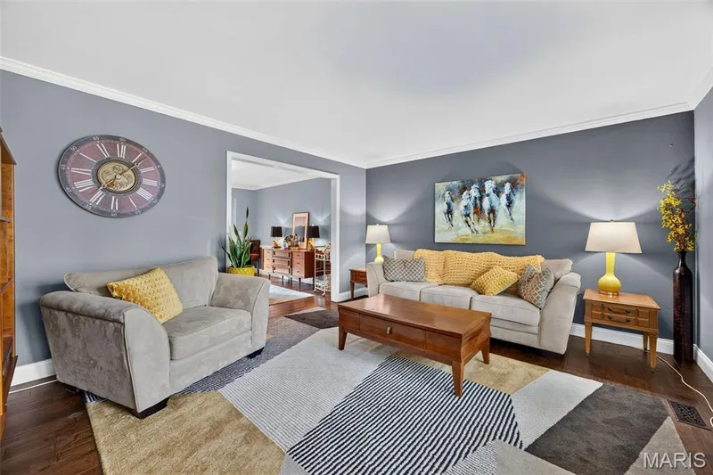 Living area featuring dark wood-finish flooring, light gray wall paint, and white crown molding — 4 Chantilly Court, Lake St. Louis, MO 63367