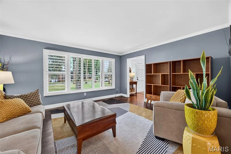 Living space with wood-finish flooring, white crown molding, and built-in shelving — 4 Chantilly Court, Lake St. Louis, MO 63367