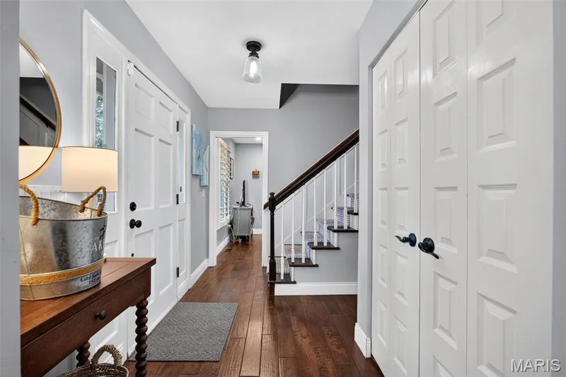 Entryway featuring wood-finish flooring and a staircase with white risers and dark treads — 4 Chantilly Court, Lake St. Louis, MO 63367