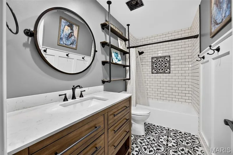 Upstairs Hall Shared Bathroom featuring a wood-finish vanity with a white countertop and matte black fixtures — 4 Chantilly Court, Lake St. Louis, MO 63367