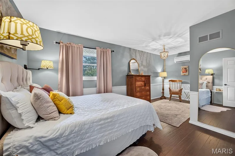 Bedroom #2 spacious interior featuring wood-finish flooring, a contemporary chandelier, and wainscoting, wall-mounted mini-split AC unit — 4 Chantilly Court, Lake St. Louis, MO 63367