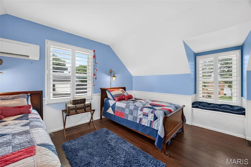 3rd Bedroom featuring wood-finish flooring, white plantation shutters, a built-in window seat with cushioning, wainscoting, and a wall-mounted mini-split AC unit — 4 Chantilly Court, Lake St. Louis, MO 63367