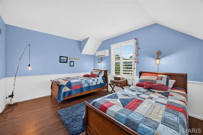 3rd Bedroom Room featuring large walk in closet, half-wall wainscoting, a vaulted ceiling, window with white plantation shutters, and a wall-mounted mini-split unit — 4 Chantilly Court, Lake St. Louis, MO 63367