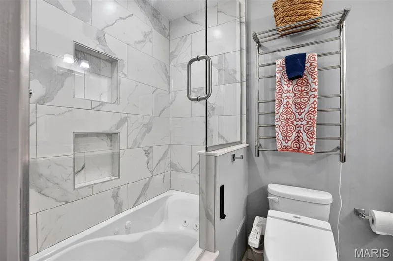 Tiled shower-tub combination featuring a glass enclosure and dual recessed niches — 4 Chantilly Court, Lake St. Louis, MO 63367