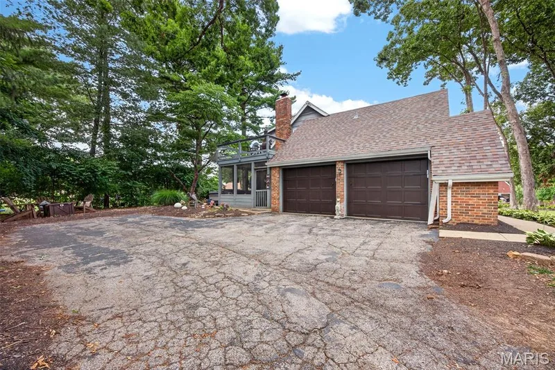 Two-car garage with brown doors, brick accents, and a shingle roof — 4 Chantilly Court, Lake St. Louis, MO 63367