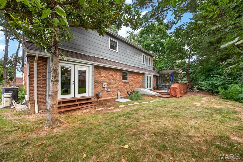 Expansive backyard featuring a multi-level deck, mature trees, and a brick and siding exterior — 4 Chantilly Court, Lake St. Louis, MO 63367