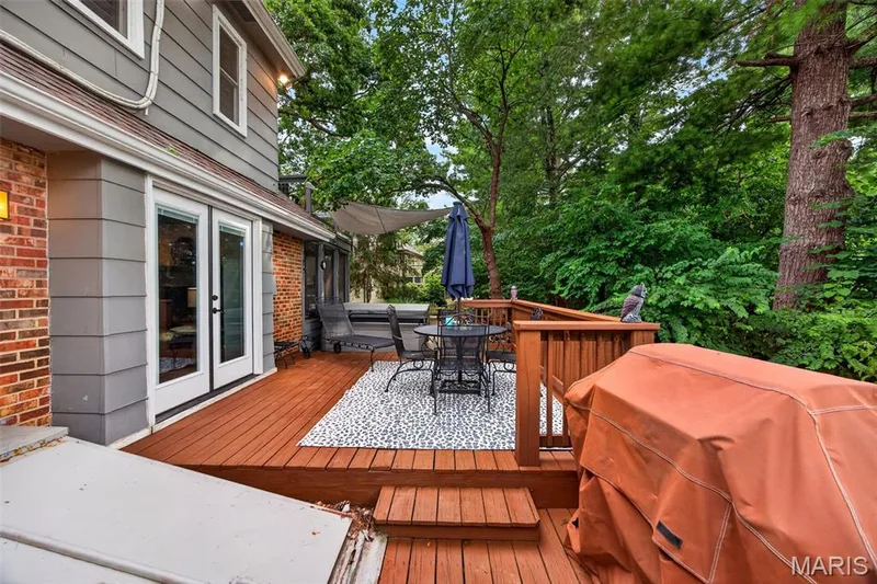 Expansive wood-finish deck with multiple levels, featuring wood railings and a privacy umbrella — 4 Chantilly Court, Lake St. Louis, MO 63367