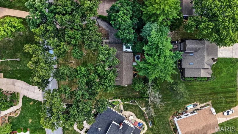 Lush, mature trees canopy the property, featuring a multi-level roofline and skylights — 4 Chantilly Court, Lake St. Louis, MO 63367