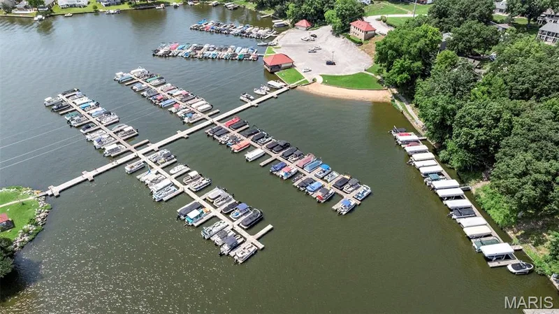 Waterfront property featuring extensive boat docks, multiple covered boat slips, and a sandy beach area — 4 Chantilly Court, Lake St. Louis, MO 63367