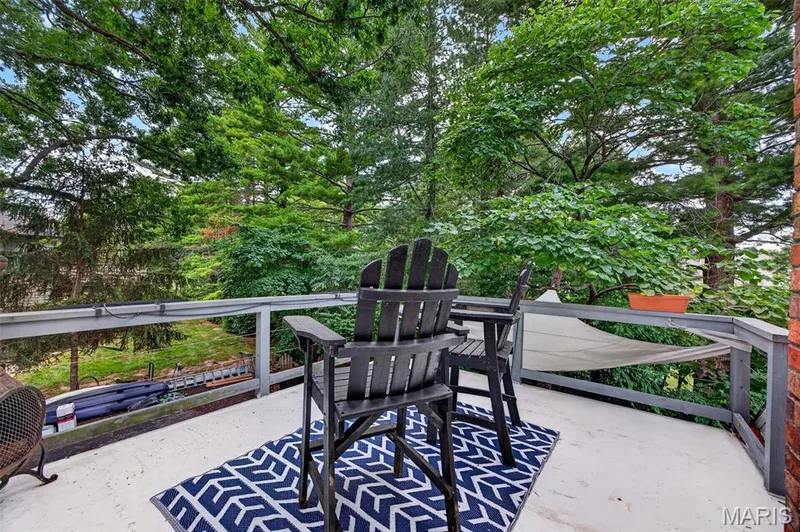 Outdoor terrace balcony featuring a neutral surface, wood railing, and surrounding mature trees — 4 Chantilly Court, Lake St. Louis, MO 63367