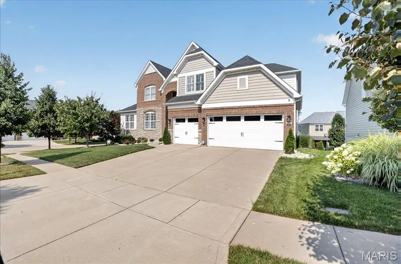 Traditional-style residence featuring a brick and stone facade, light-toned siding, and a prominent two-car garage — 302 Oak Stand Court, Chesterfield, MO 63005