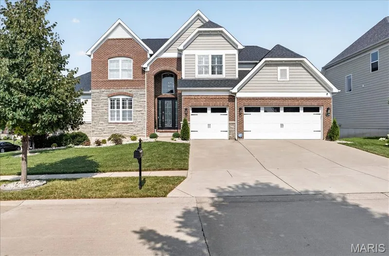 Two-story residential exterior featuring brick and stone veneer, light gray siding, and a prominent arched entryway — 302 Oak Stand Court, Chesterfield, MO 63005