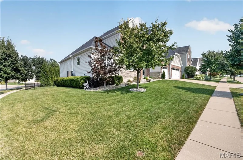 Spacious lawn featuring mature trees and shrubbery, with a concrete sidewalk bordering the property — 302 Oak Stand Court, Chesterfield, MO 63005
