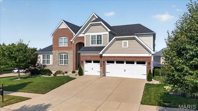 Two-story residence featuring a brick and stone facade, gabled rooflines, and a two-car garage with individual doors — 302 Oak Stand Court, Chesterfield, MO 63005