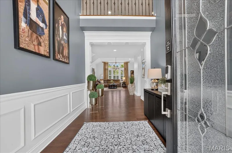 Grand entry featuring a decorative glass door, rich wood-finish flooring, and wainscoting details — 302 Oak Stand Court, Chesterfield, MO 63005