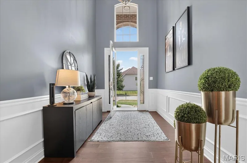 Two-story foyer featuring wood-finish flooring, wainscoting, and a decorative front entry door with sidelights — 302 Oak Stand Court, Chesterfield, MO 63005