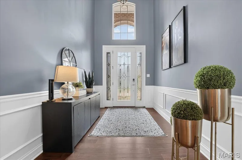 Gracious entryway featuring a decorative glass paneled front door, an arched transom window, wainscoting, and wood-finish flooring — 302 Oak Stand Court, Chesterfield, MO 63005