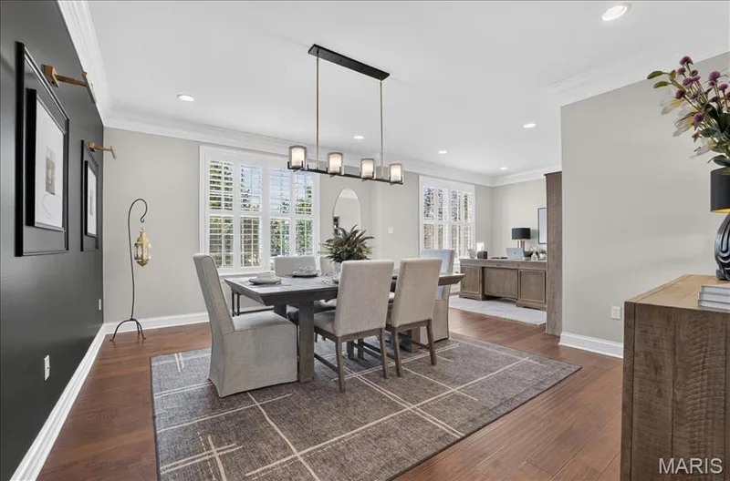 Dining area featuring rich wood-finish flooring and a contemporary linear chandelier — 302 Oak Stand Court, Chesterfield, MO 63005