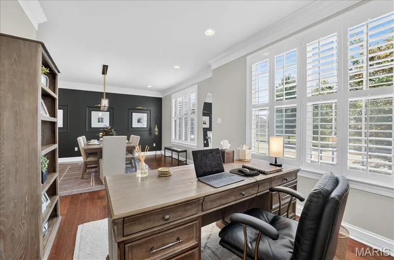 Expansive interior featuring wood-finish flooring, white crown molding, and large windows with plantation shutters — 302 Oak Stand Court, Chesterfield, MO 63005