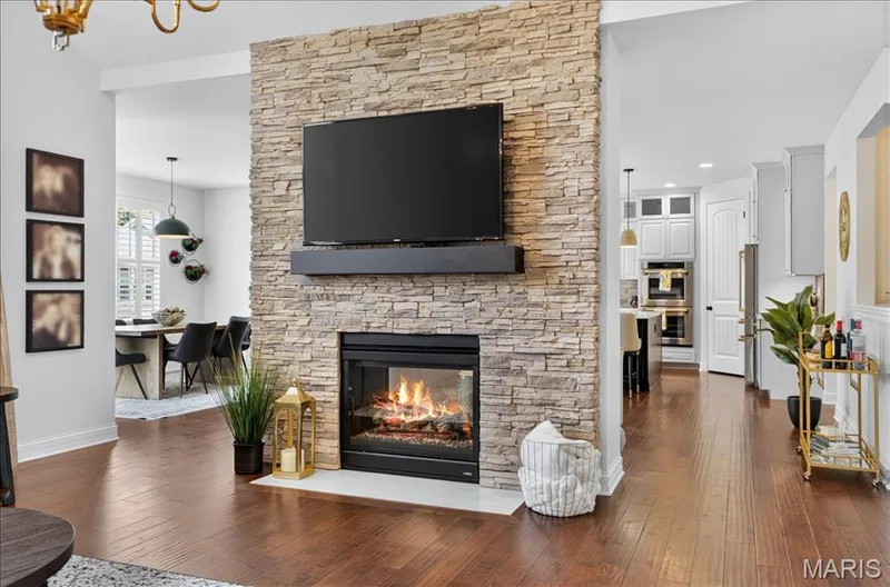Stacked stone fireplace with a white hearth, dark wood-finish flooring, and white wall finishes — 302 Oak Stand Court, Chesterfield, MO 63005