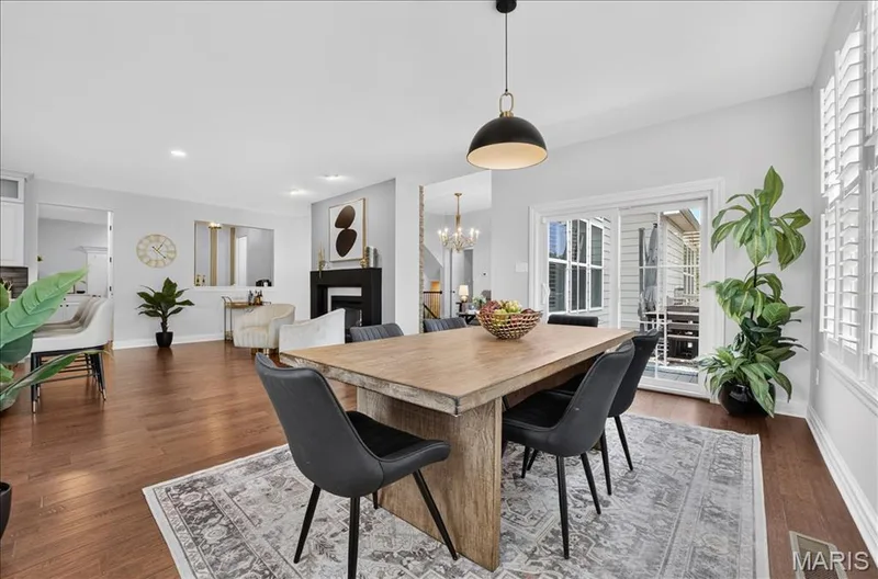 Dining area featuring wood-finish flooring, a contemporary pendant light fixture, and white plantation shutters — 302 Oak Stand Court, Chesterfield, MO 63005
