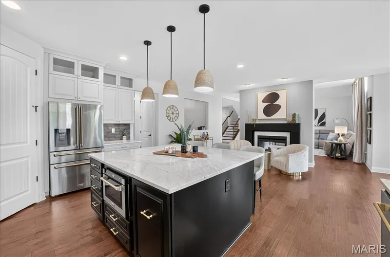 Open-concept kitchen with a large island featuring a white countertop and dark cabinetry — 302 Oak Stand Court, Chesterfield, MO 63005