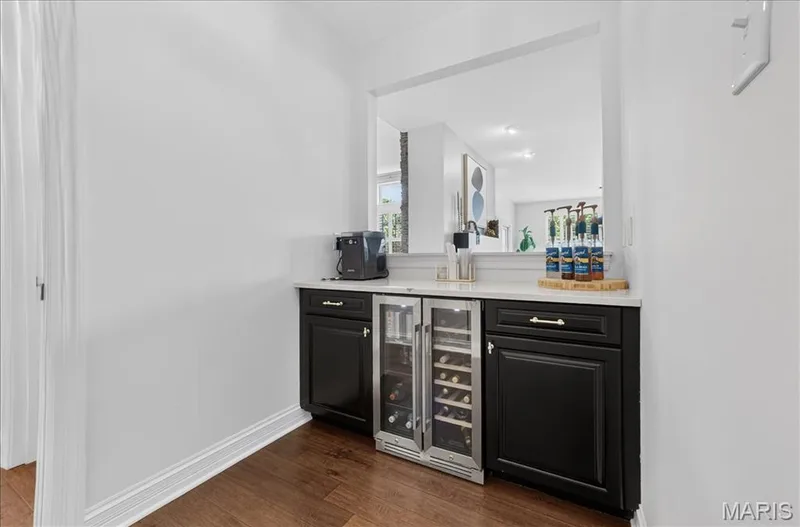 Built-in bar area featuring dark cabinetry, light countertop, and wood-finish flooring — 302 Oak Stand Court, Chesterfield, MO 63005