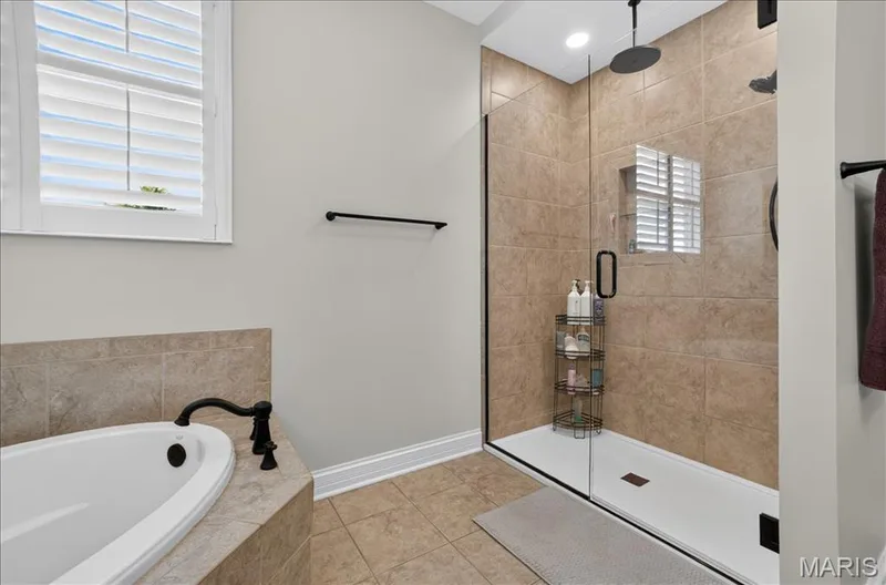 Walk-in shower with clear glass enclosure and rain shower head, featuring tan tile surround — 302 Oak Stand Court, Chesterfield, MO 63005