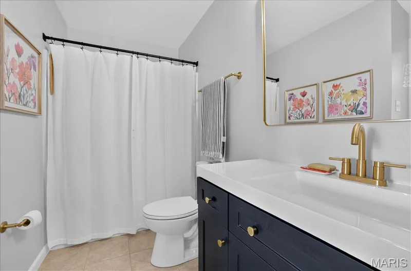 Bathroom featuring a dark blue vanity with gold-finish hardware, a white integrated sink, and a gold-finish faucet — 302 Oak Stand Court, Chesterfield, MO 63005
