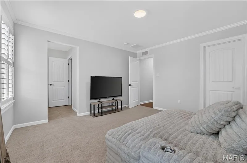 Carpeted room featuring light gray walls, white trim, and white plantation shutters — 302 Oak Stand Court, Chesterfield, MO 63005